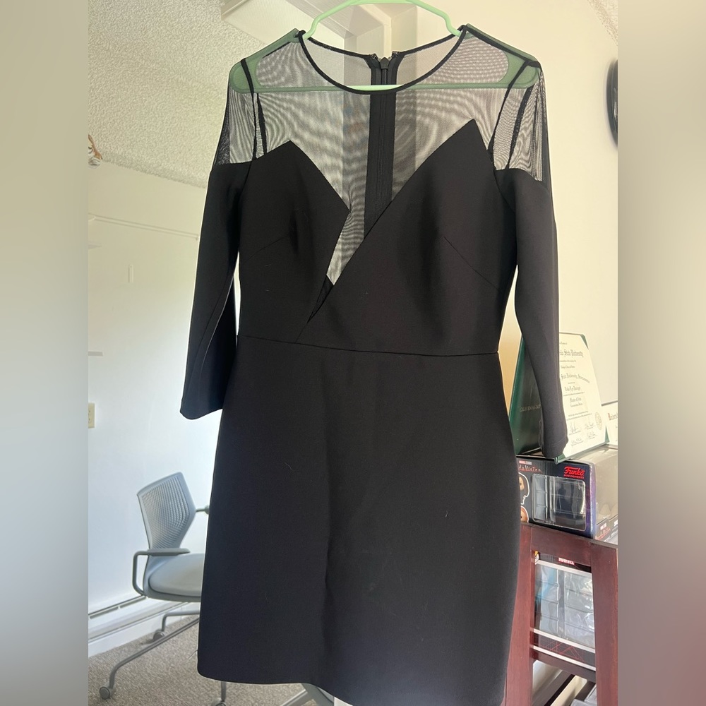 Black cocktail dress with sheer material over chest area.